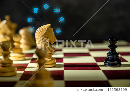 Knight chess piece with glowing business icons standing against a pawn chess piece on the chessboard. Concept of Business new idea or strategy 133568209