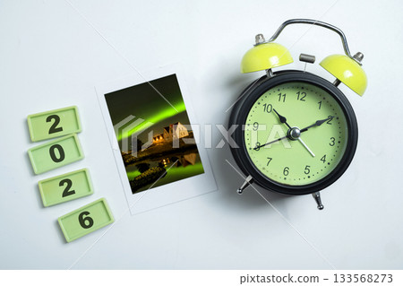 Instant print of the view of the aurora and an alarm clock with rectangular blocks spelling the year 2026. Mockup or Copy space. Happy New Year concept or Celebration 133568273