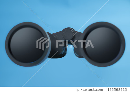 Black binoculars on a blue background. Concept of travel, summer, or vacation 133568313