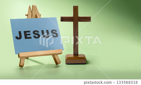 Christian cross and white paper with Jesus text on a green background. Concept of Christianity, religious, faith, Jesus, or belief Christian cross and white paper with Jesus text on a green background. Concept of Christianity, religious, faith, Jesus, or belief 133568318