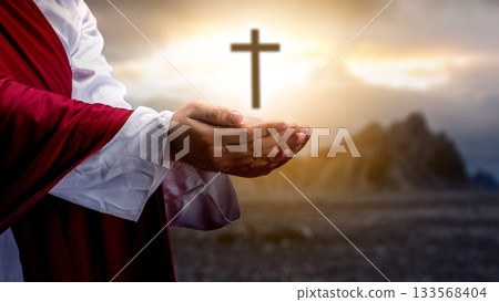 Jesus Christ raising his hand and praying with the Christian cross on the hill with dark dramatic sky background. Concept of Christianity, religious, faith, Jesus, or belief 133568404