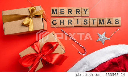 Greeting of Merry Christmas text with a gift box and a candy cane on a red background. Holiday greetings or winter themes. Concept of the Merry Christmas celebration 133568414
