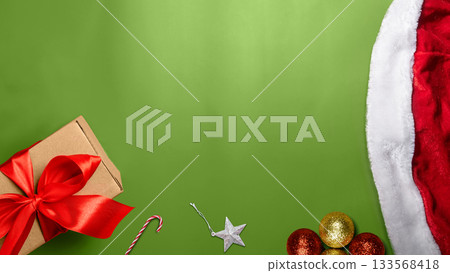 Santa hat, Christmas ornament decoration and gift box on a green background. Mockup or Copy space. Holiday greetings or winter themes. Concept of the Merry Christmas celebration Santa hat, Christmas ornament decoration and gift box on a green background. Mockup or Copy space. Holiday greetings or winter themes. Concept of the Merry Christmas celebration 133568418