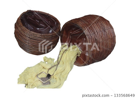 Wicker basket spilling a yellow cloth and necklace 133568649