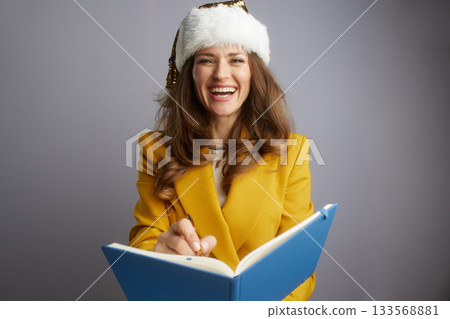 Laughing Businesswoman in Santa Hat with Notebook Laughing Businesswoman in Santa Hat with Notebook 133568881