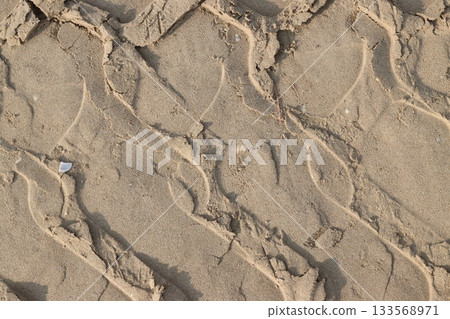 Tire tracks creating a pattern on the sandy surface Tire tracks creating a pattern on the sandy surface 133568971