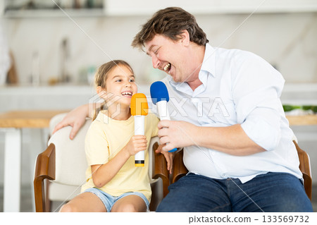 Karaoke time - father and daughter sing into microphones 133569732