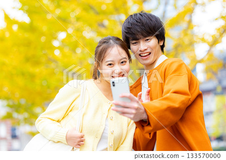 A couple taking a selfie in front of a ginkgo tree A couple taking a selfie in front of a ginkgo tree 133570000