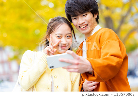 一對情侶在銀杏樹前自拍。 133570002