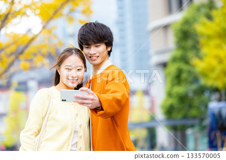 一對情侶在銀杏樹前自拍。 133570005