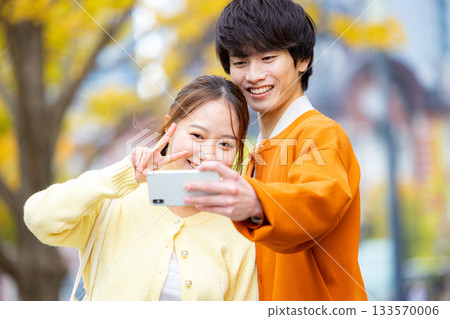 一對情侶在銀杏樹前自拍。 133570006