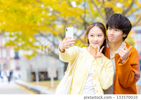 一對情侶在銀杏樹前自拍。 133570010