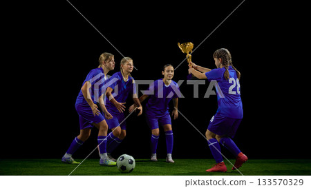 Teenage soccer player presenting trophy to teammates during post-match moment 133570329