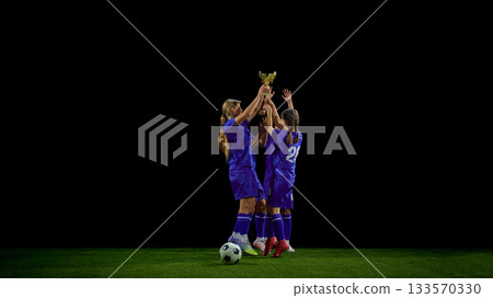 Teenage soccer team raising trophy together in victory moment 133570330