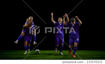 Teenage soccer players celebrating win with mixed running and lifting gestures 133570331