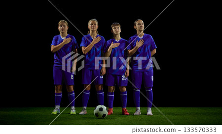Teenage soccer players standing with hand on chest during anthem moment Teenage soccer players standing with hand on chest during anthem moment 133570333