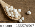 White dry tapioca pearls in wooden scoop on wooden background closeup. Raw tapioca starch balls used for bubble tea or desserts. Tapioca pearls as healthy gluten free ingredient. 133570507