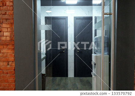 Modern office hallway featuring two closed doors and a water cooler 133570792