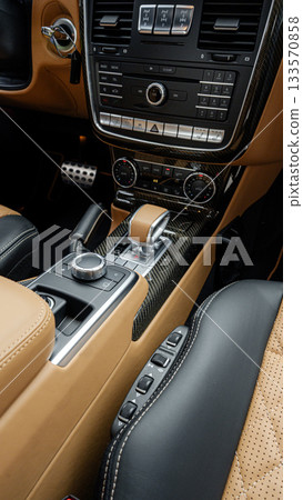 Luxury car interior showing detailed gear shift and controls in soft leather and metallic accents Luxury car interior showing detailed gear shift and controls in soft leather and metallic accents 133570858