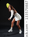 Young woman practicing tennis skills in a studio with a black background 133570887