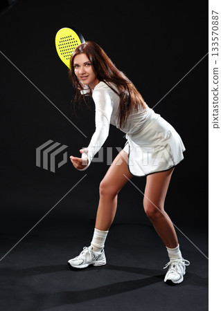Young woman practicing tennis skills in a studio with a black background Young woman practicing tennis skills in a studio with a black background 133570887