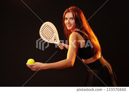 Woman preparing to serve in a racket sport with a bright smile and a tennis ball Woman preparing to serve in a racket sport with a bright smile and a tennis ball 133570888