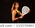 Female player poses confidently with a paddle in a dark studio setting 133570901