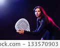 Engaging woman preparing for a padel game in a dynamic indoor setting 133570903