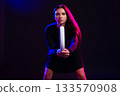 Woman posing with a lighting rod in a colorful studio environment for a creative photo shoot 133570908
