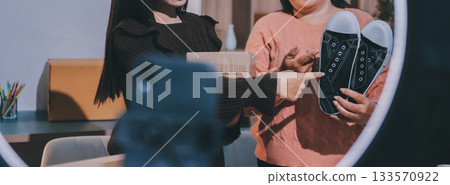 Asian woman describe selling clothes on camera live broadcast on social network at home, Online selling clothes on social media. Blogger woman influencer, SME retail store owner. 133570922