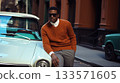 A Chic and Stylish black Man Dressed in Retro Attire Posing Next to a Beautiful Vintage Car. Male African American model 133571605