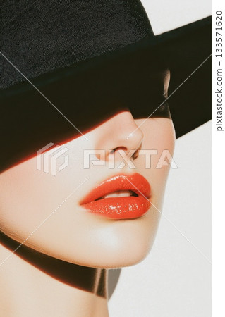 Sophisticated woman wearing wide brimmed black hat, black turtleneck, sporting bold red lipstick 133571620