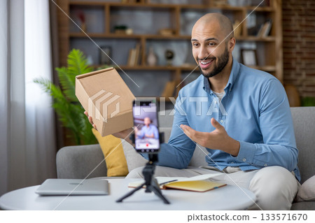 Content creator man filming a product unboxing video on smartphone for social media audience, sharing experiences and recommendations for online shopping and e-commerce Content creator man filming a product unboxing video on smartphone for social media audience, sharing experiences and recommendations for online shopping and e-commerce 133571670