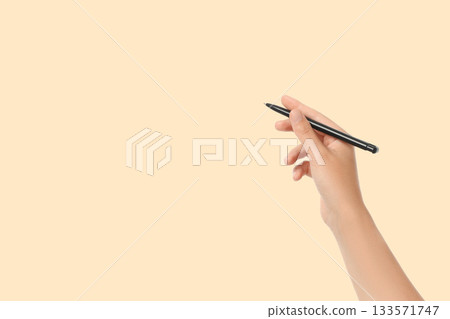 A person holds a black pen ready to write on a smooth surface 133571747