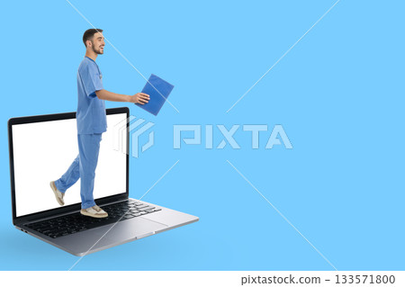 A doctor in blue scrubs carries files from a laptop 133571800