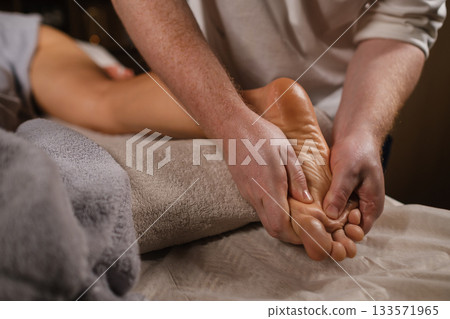 Relaxing foot massage at a wellness center during a soothing evening session Relaxing foot massage at a wellness center during a soothing evening session 133571965