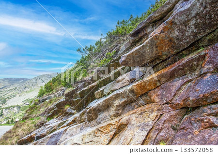Rocky alpine hillside with dripping meltwater and blue sky Rocky alpine hillside with dripping meltwater and blue sky 133572058