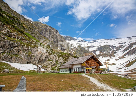 Alpine lodge near Kolnbrein reservoir with snowy mountain backdrop 133572089