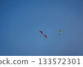 Brightly colored paramotors fly in tight groups across a clear, calm sky during a daytime adventure. 133572301