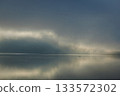 Misty Lake Dawn With Small Boat, Silent Water and Soft Reflections 133572302