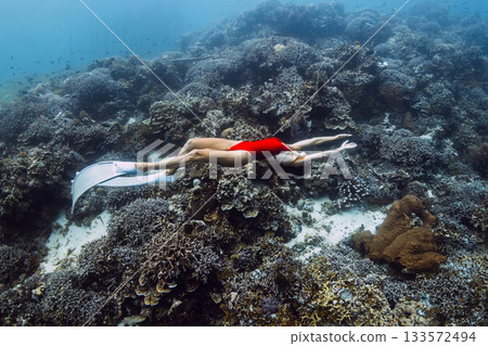 Freediver woman glides in underwater with living corals. Free diving in Raja Ampat Freediver woman glides in underwater with living corals. Free diving in Raja Ampat 133572494
