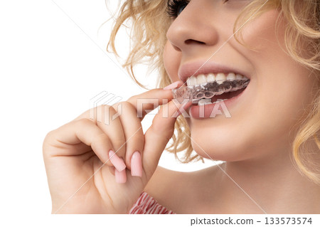 Woman preps with clear aligner by her smile, isolated, PNG 133573574