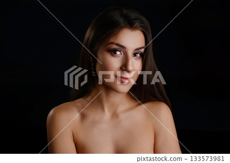 Portrait of beautiful young woman with dark hair against black background Portrait of beautiful young woman with dark hair against black background 133573981