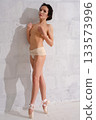 Ballet dancer posing gracefully against a white wall in a studio setting 133573996