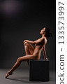 Elegant female figure in artistic pose against a dark background during a studio shoot 133573997