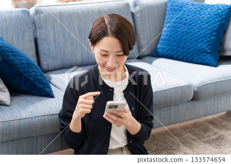 操縱帶沙發的智能手機的女人 133574654