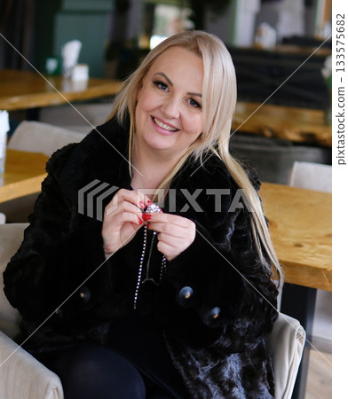 woman in fur coat poses, puts on long earrings, takes off fur coat, and has long blonde hair. fur coat, she examines it and touches the quality. Buying outerwear for winter. woman in fur coat poses, puts on long earrings, takes off fur coat, and has long blonde hair. fur coat, she examines it and touches the quality. Buying outerwear for winter. 133575682