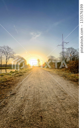 Experience a Serene Sunrise on a Beautiful Pathway That Leads Through Lush Nature Experience a Serene Sunrise on a Beautiful Pathway That Leads Through Lush Nature 133576399