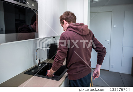 Man washing dishes in modern kitchen sink 133576764