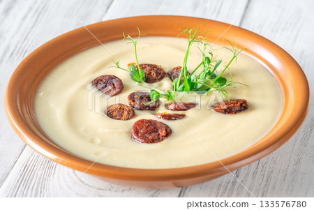 Creamy cauliflower soup with spicy chorizo served warmly in terracotta bowl on white table Creamy cauliflower soup with spicy chorizo served warmly in terracotta bowl on white table 133576780